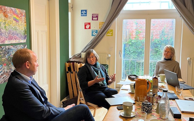 Drei Menschen sitzen an einem Tisch und reden miteinander