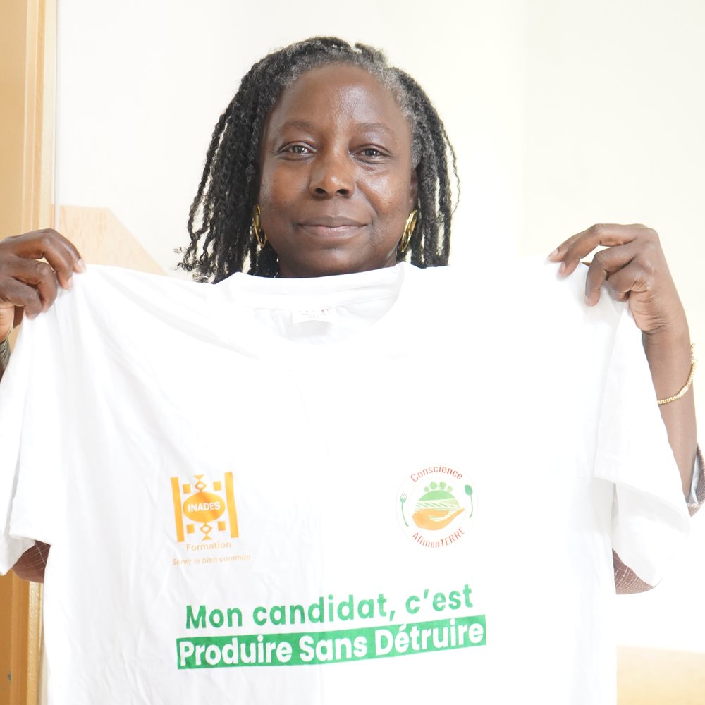 Pauline Zei hält ein T-Shirt hoch mit der Aufschrift "Mein Ansatz lautet: Produzieren, ohne zu zerstören."