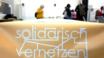 Auf einer Tischdecke steht Solidarisch vernetzen