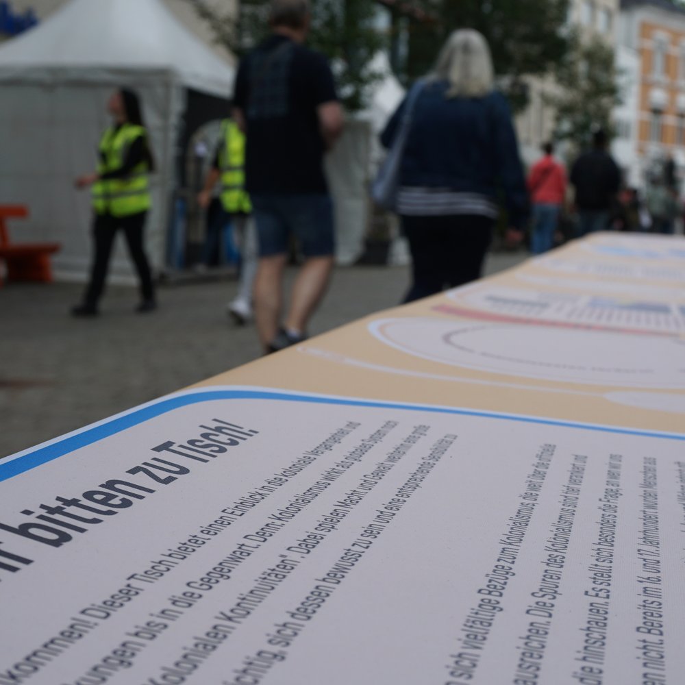 Wir bitten zu Tisch, die Einleitung zur Ausstellung Das Dinner lädt die Menschen zur Beschäftigung mit kolonialen Kontinuitäten in Niedersachsen ein