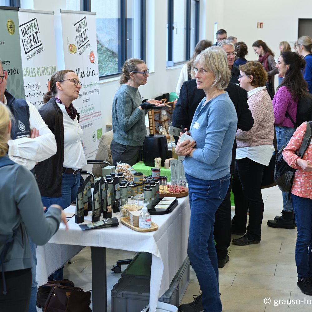 Menschen stehen an Ess-Ständen und unterhalten sich