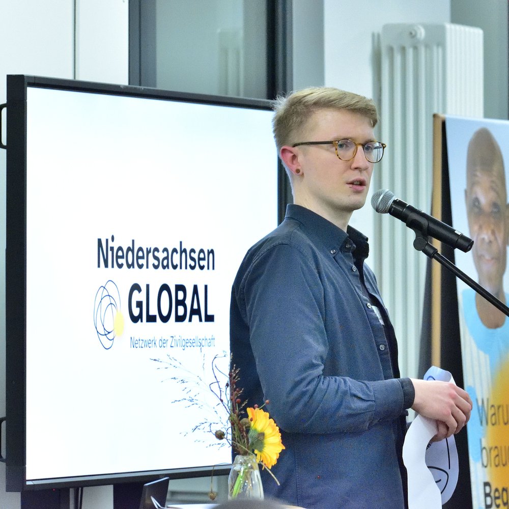 Matti Linke steht an einem Mikophon und trägt einen text vor