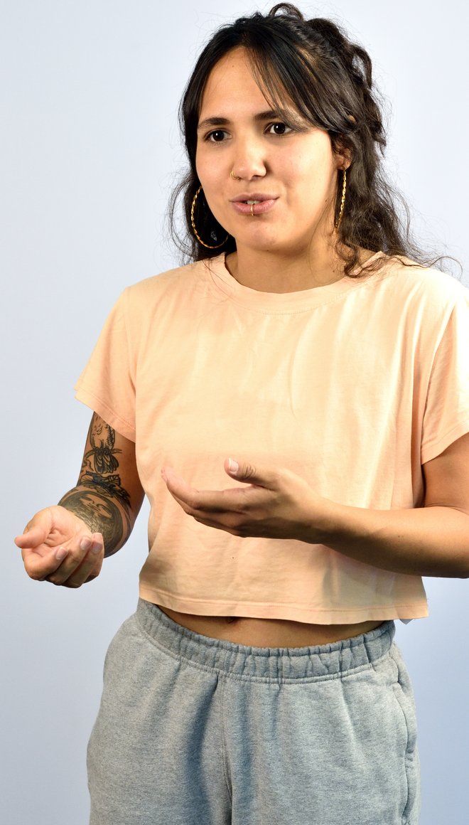 Ein junger Mensch mit einem hellen Oberteil und weißer Haut spricht und gestekuliert dabei