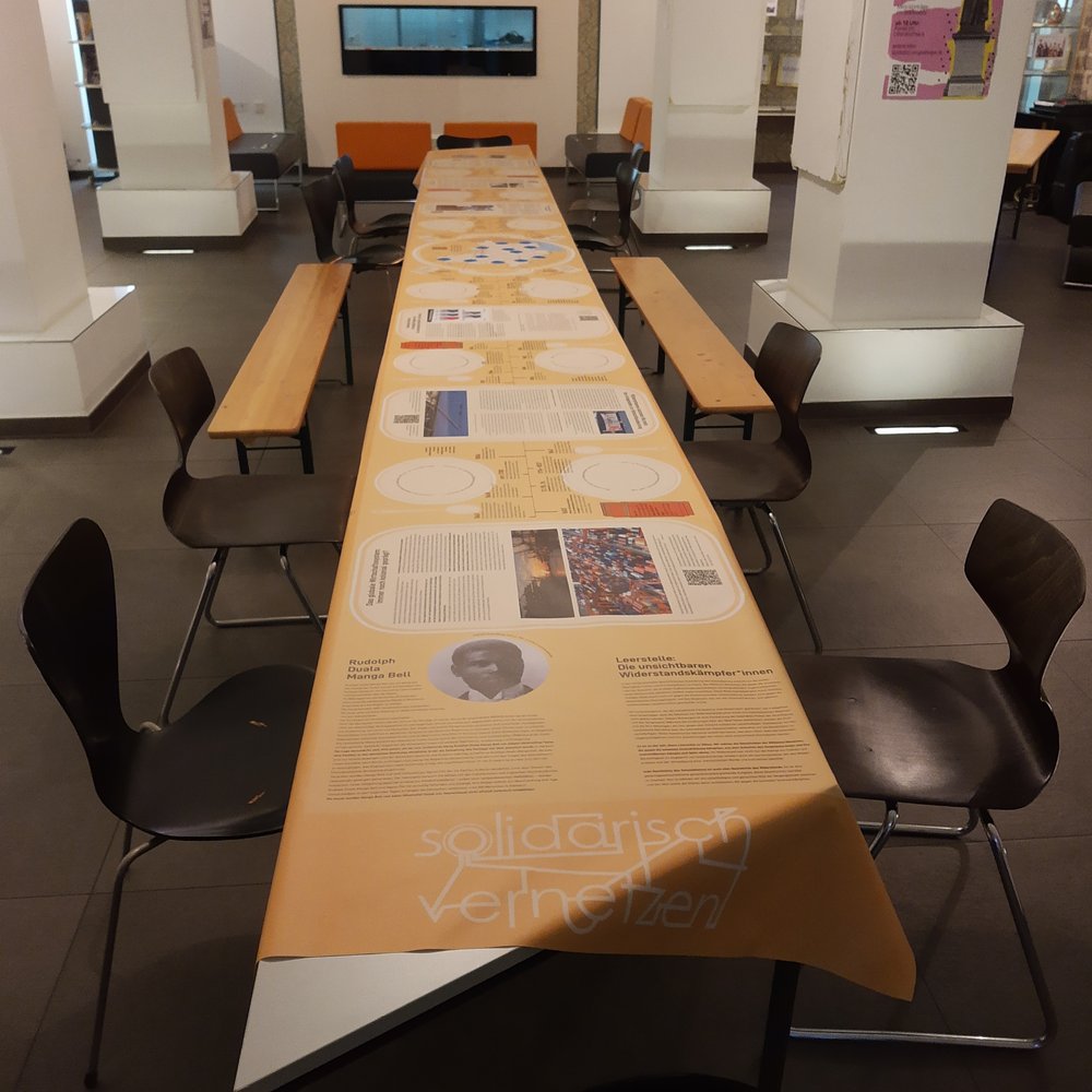 Die Ausstellung das Dinner, ein 6m langes Tischtuch im Stadtlabor Göttingen auf einem Tisch.