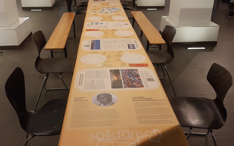 Die Ausstellung das Dinner, ein 6m langes Tischtuch im Stadtlabor Göttingen auf einem Tisch.