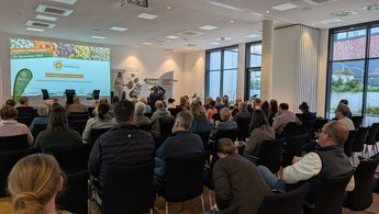 Menschen sitzen vor einer Bühne