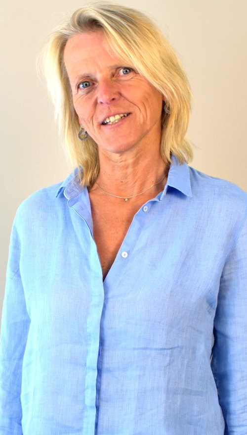 Portrait von Katrin Beckedorf, die mittellange blonde Haare und weiße Haut hat und ein blaues Hemd trägt