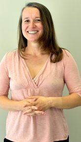 Portrait von Natalia Spetter, die lange braune Haare und eine weiße Haut hat und eine rosa Bluse trägt