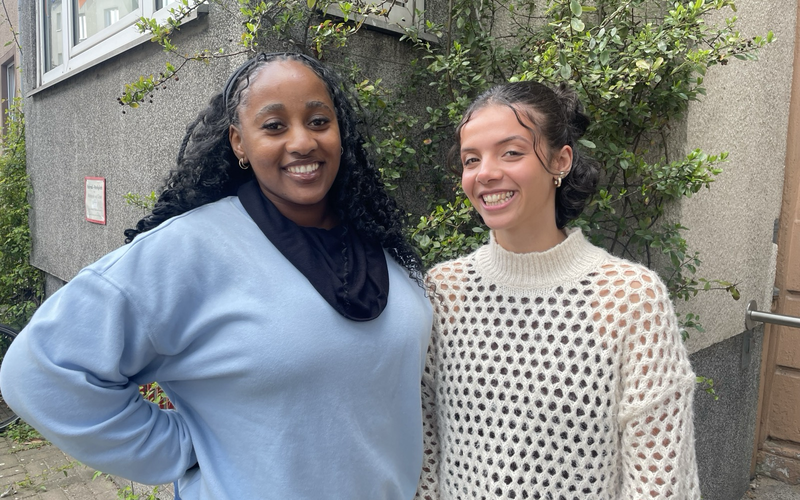 Thamie und Laila stehen lachend vor einem Haus