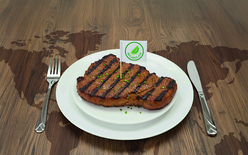 ein Steak auf einem Teller mit Fähnchen "pflanzlich"