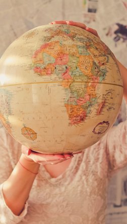 Ein Mensch hält einen Globus vor ihren Kopf