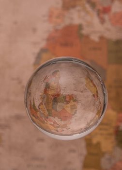 Eine Glaskugel schwebt vor einer Weltkarte, in ihr sieht man die Karte gespiegelt und auf den Kopf gestellt